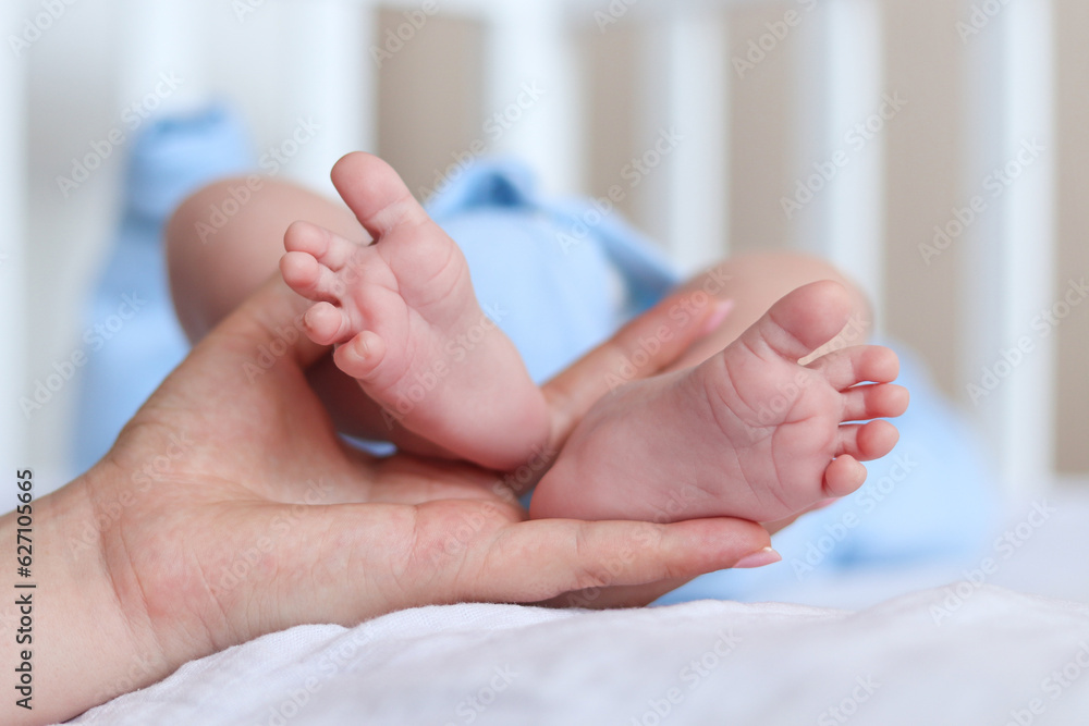 Little heels of a newborn baby in mother's hand. Selective focus, close-up Little heels of a newborn baby in mother's hand. Selective focus, close-up