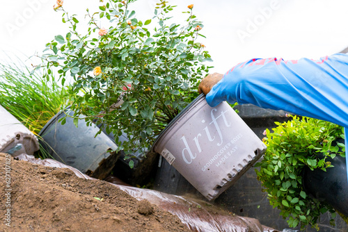 Landscaping Company Tending to A Front Lawn, Flower Bed Cutting Grass, Blowing Debris, and A Retaining Wall