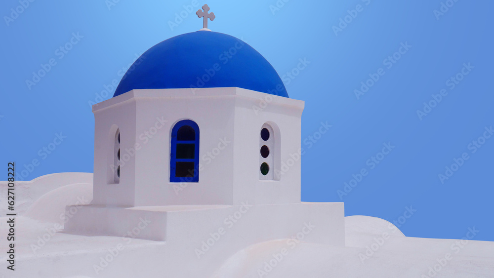 White traditional chapel with blue dome of Oia village on Santorini island, Greece.