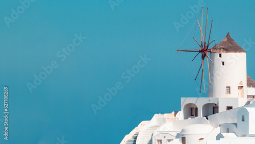 View of a Santorini hill and old traditional windmill on copy-space blue sky.