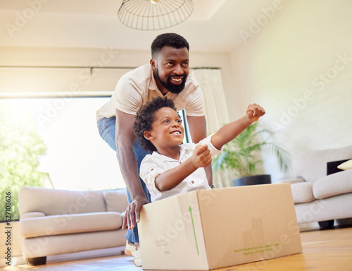 Father, son and playing at home with pretend car in a box on moving day in new property. Black family, house and real estate move of a dad and child together with play driving and fun in living room