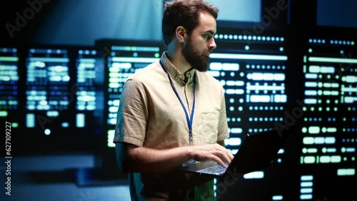 Close up of adept technician using laptop to check operational server hub. Hardware clusters in data storage and cloud computing business service providing processing for several workloads