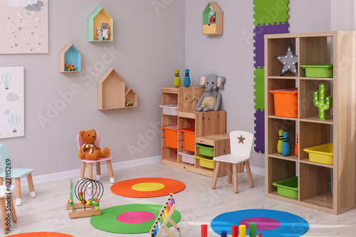 Child`s playroom with different toys and furniture. Cozy kindergarten interior