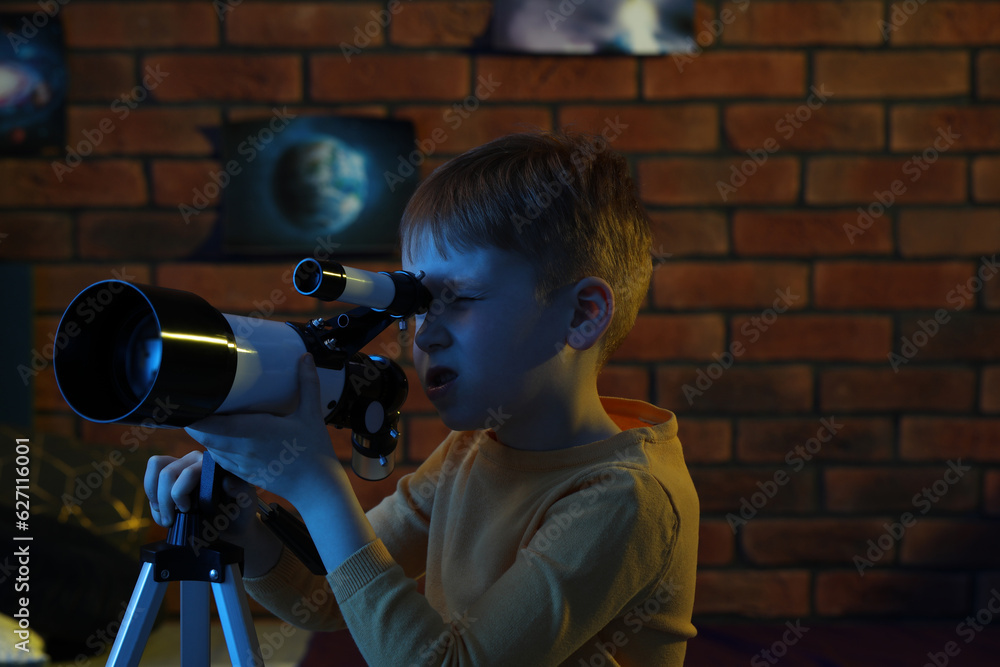 Little boy looking at stars through telescope in room Little boy looking at stars through telescope in room