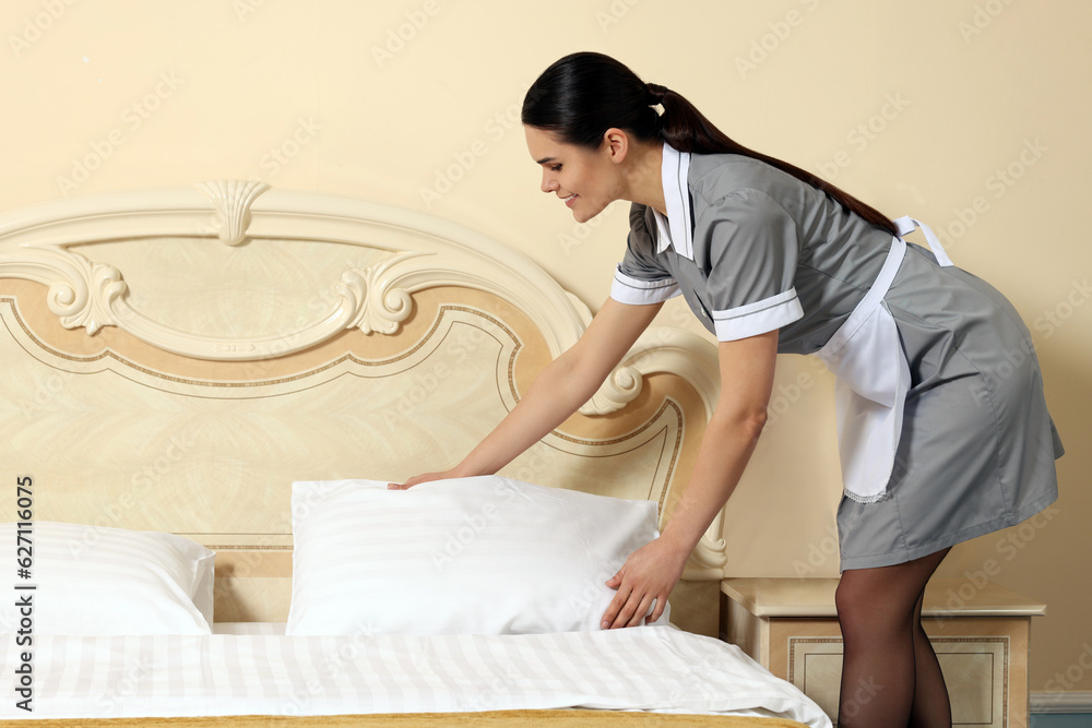 Young chambermaid making bed in hotel room. Space for text Young chambermaid making bed in hotel room. Space for text