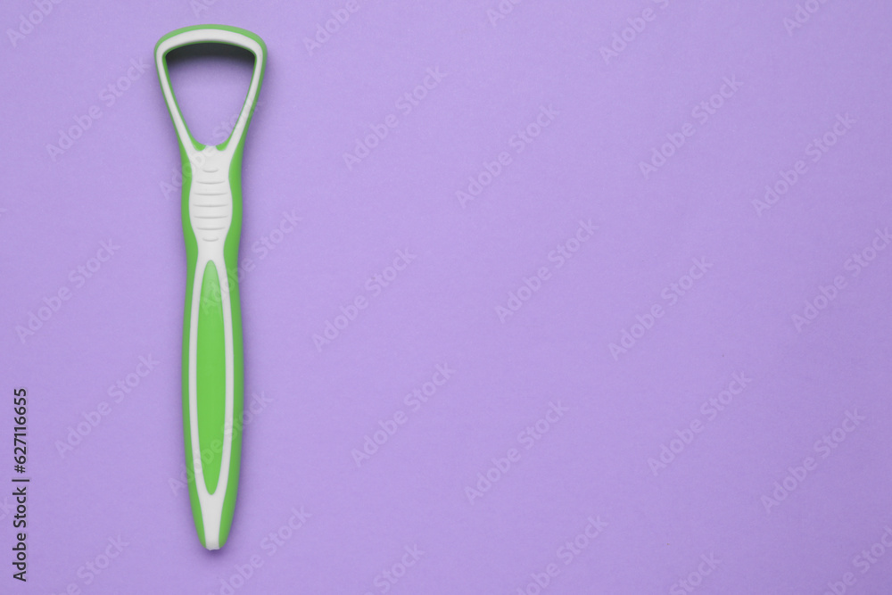 Green tongue cleaner on violet background, top view. Space for text Green tongue cleaner on violet background, top view. Space for text