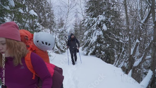 Girl in pink jacket walking mountain trail covered in deep snow. Climbing Pietrosul Rodnei in winter. Couple on climbing expedition with poles. photo