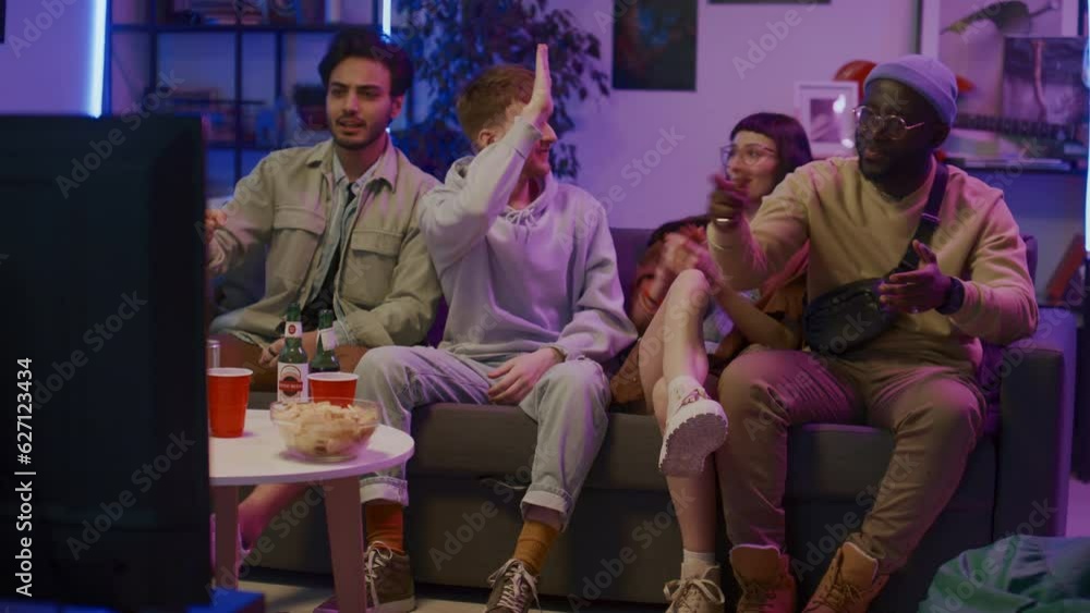 Full shot of four multiethnic zoomers sitting on couch in living room