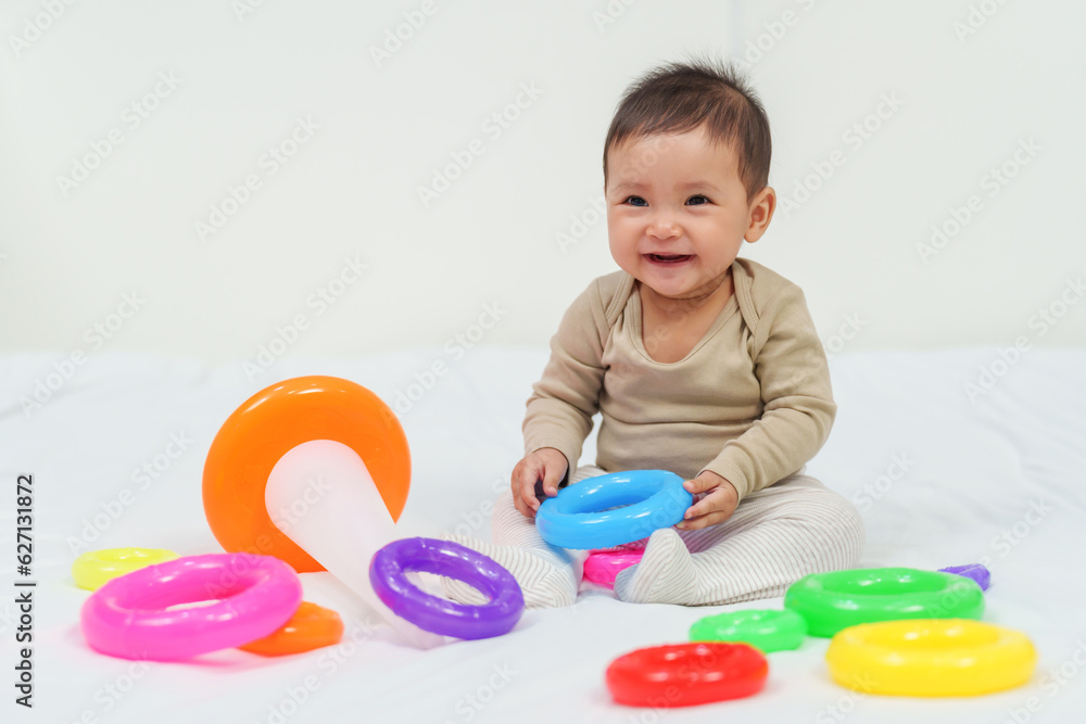 infant baby playing the pyramid toy with colored rings on bed infant baby playing the pyramid toy with colored rings on bed