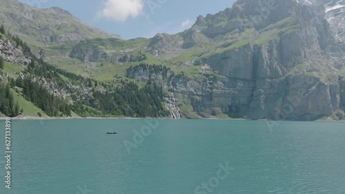 Aerial drone view of small boat on alpine lake, exploring the Swiss Alps on a sunny day