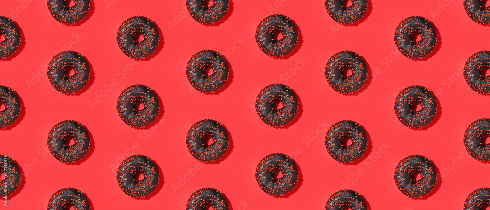 Many delicious chocolate donuts on red background, top view. Pattern for design Many delicious chocolate donuts on red background, top view. Pattern for design
