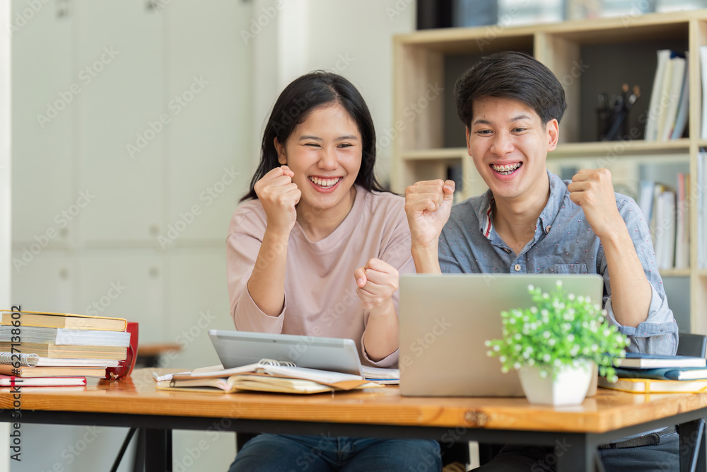 Two Asian students learning together and tutor together at cafe and a celebrate while watching exam results Two Asian students learning together and tutor together at cafe and a celebrate while watching exam results