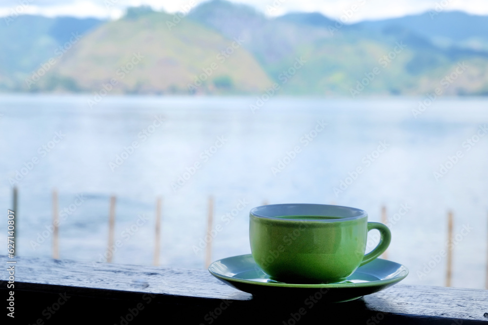 a cup of milk green tea on the table beside lake. the addition of milk to green tea may help mitigate the potential bitterness or astringency of some green teas, making it more enjoyable.