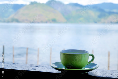 a cup of milk green tea on the table beside lake. the addition of milk to green tea may help mitigate the potential bitterness or astringency of some green teas, making it more enjoyable.