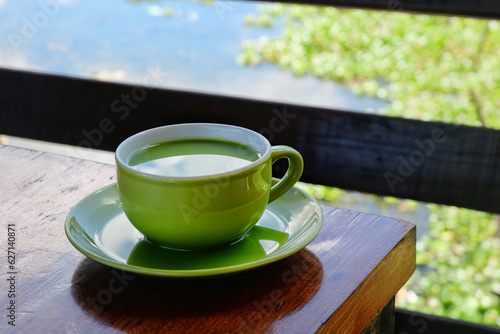 Fototapet a cup of milk green tea on the table beside lake