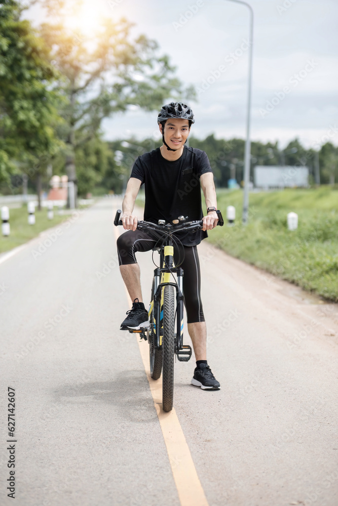 Obraz premium Shot of happy asian guy enjoying biking in the summer park. Sport, leisure and healthy lifestyle concept