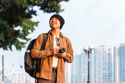 Asian male tourist holding a camera is traveling in the city. 