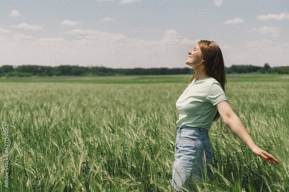 A woman enjoys the fresh air in nature in a green barley field. Summer countryside and gathering flowers. Atmospheric tranquil moment A woman enjoys the fresh air in nature in a green barley field. Summer countryside and gathering flowers. Atmospheric tranquil moment