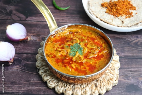 Traditional Sev bhaji or sev tamatar nu Shaak with Jowar Bhakri. Sev is a crisp fried gram flour vermicelli. Served with chopped onion and lemon. with Copy space. Its a sweet and spicy indian curry. photo