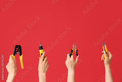 Electrician hands with tools on red background