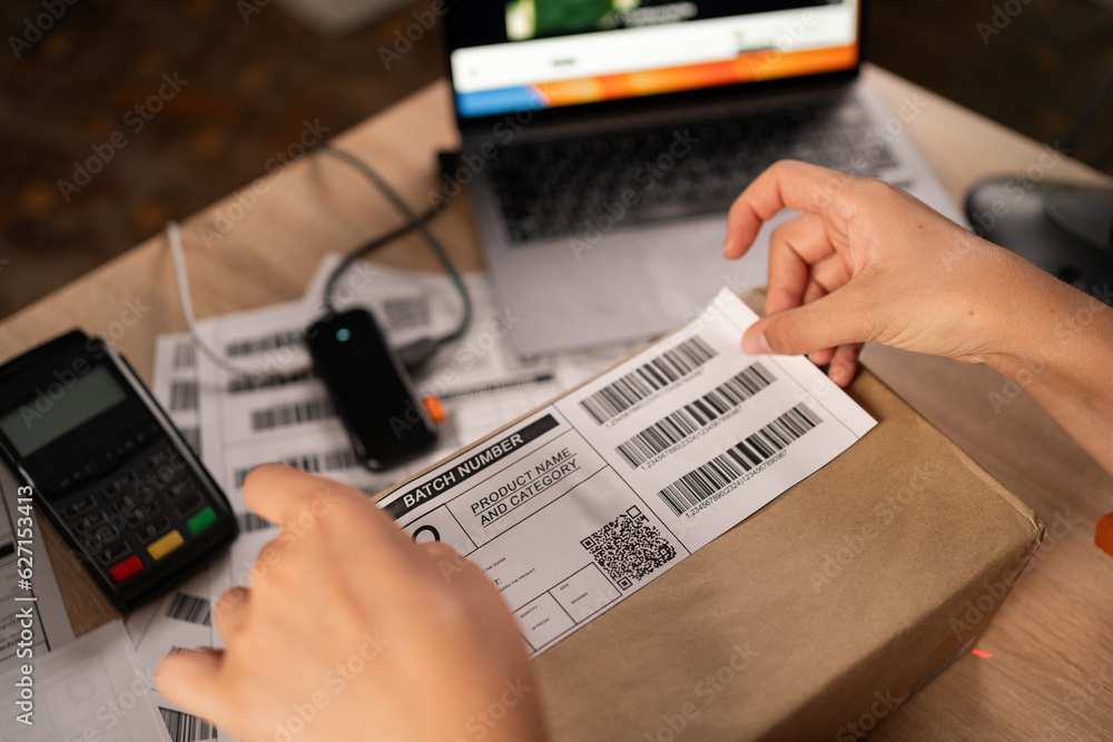Woman employee glue barcode on delivery parcel. Worker packing