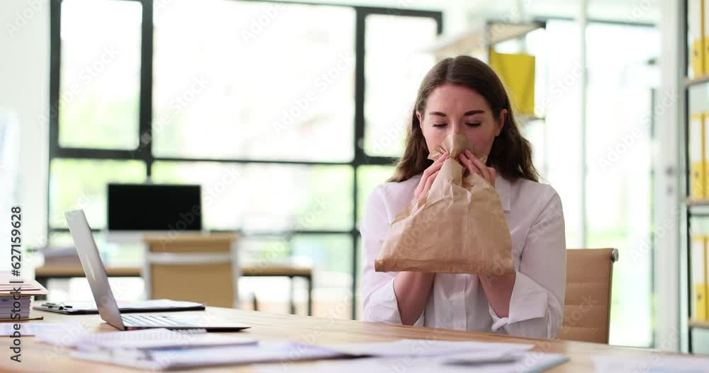 Woman having panic attack at workplace breathing into paper bag. Stress panic fear in office Woman having panic attack at workplace breathing into paper bag. Stress panic fear in office
