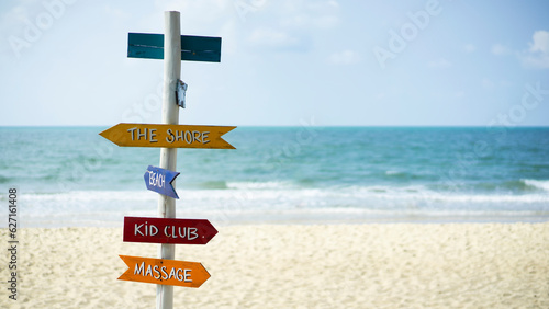 Signs pointing on a tropical beach against the background of the sea and beach. Beautiful white sand beach wiht colorful signs. 