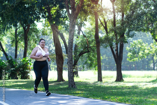 Oversized woman jogging at public park in the morning, weight loss concept