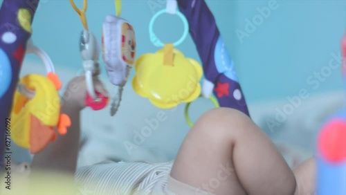 low angle video: baby's hands are playing with a toy that is hung above the bed to stimulate the baby's motor development. Baby hand-play hanging toys