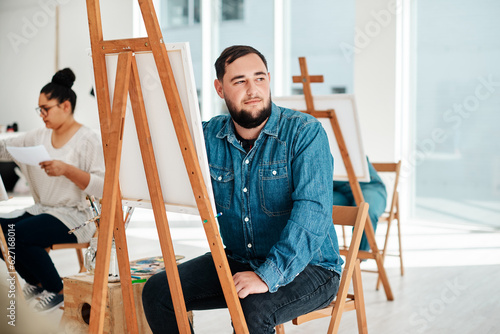 I wonder what colour I should use. Cropped shot of a handsome young artist sitting and looking contemplative during an art class in the studio.