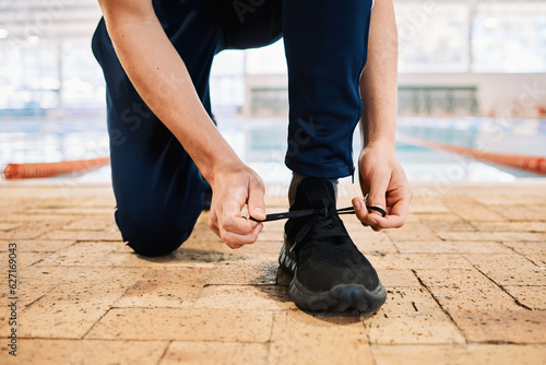 Man, hands and tying shoes by pool for workout, exercise or training preparation indoors. Closeup of male person or athlete tie shoe and getting ready for sports exercising, fitness or competition