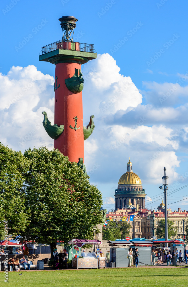 Rostral column on Vasilyevsky island spit with Saint Isaac's cathedral dome at background, St. Petersburg, Russia Rostral column on Vasilyevsky island spit with Saint Isaac's cathedral dome at background, St. Petersburg, Russia
