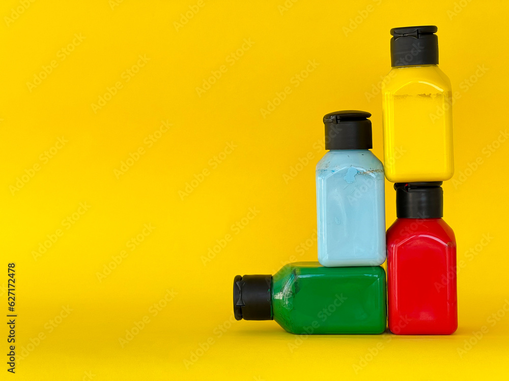 Jars with bright multi-colored acrylic paint on a yellow background. Still life Jars with bright multi-colored acrylic paint on a yellow background. Still life