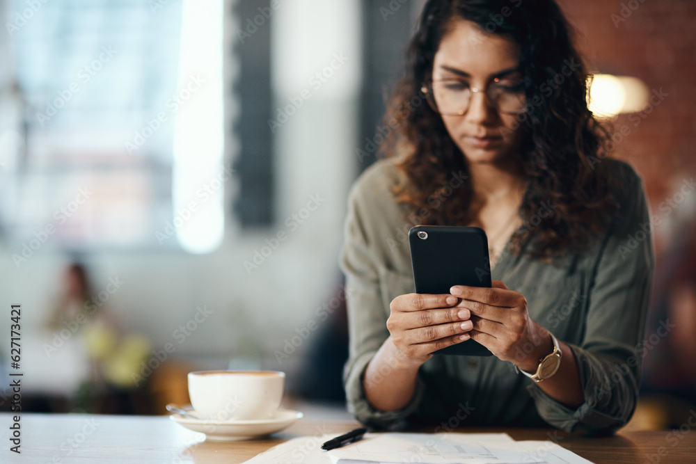 Its a freelancers world and were all living in it. Shot of a young woman using a smartphone while working in a cafe.