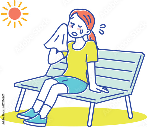 暑い夏、ハンカチで汗を拭いてベンチで休憩する若い女性
