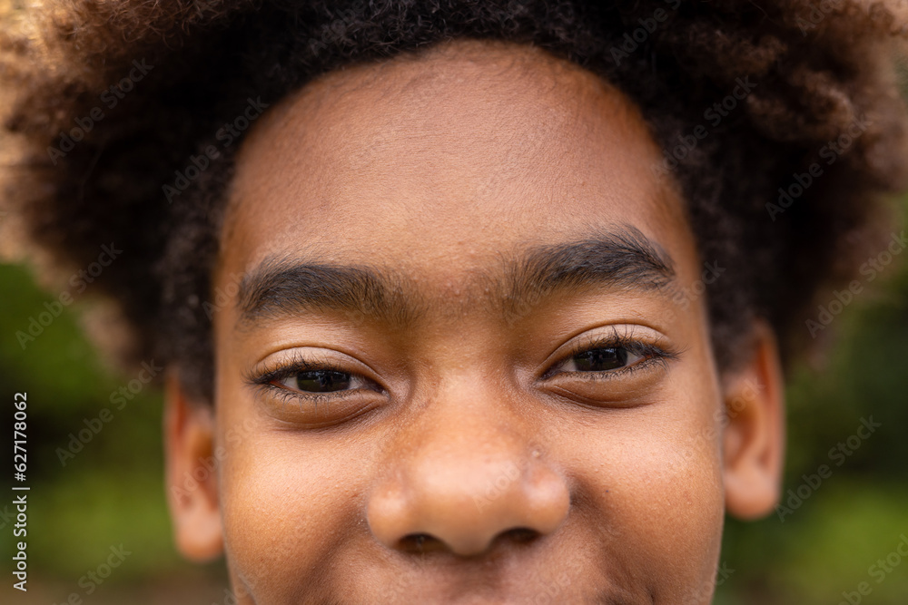 Portrait of happy african american boy looking at camera and smiling in garden