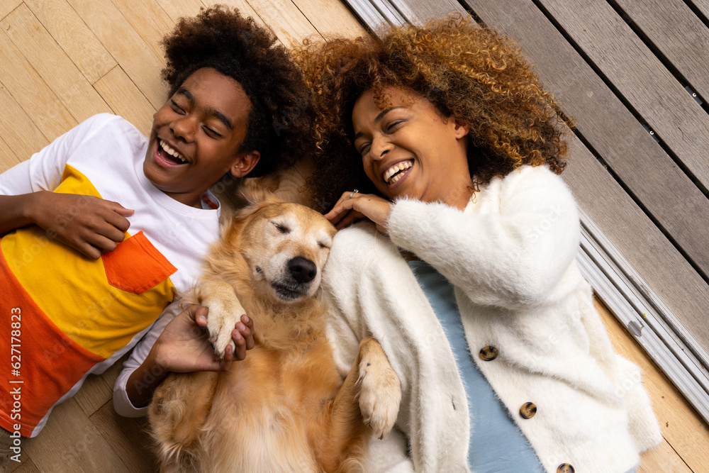 Happy african american mother and son lying on floor with their pet dog Happy african american mother and son lying on floor with their pet dog