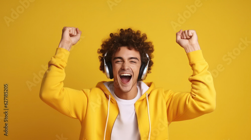 Studio shot of overjoyed teenage couple dance with raised hands, enjoy cool music in stereo headphones, listen pleasant popular track, move actively against yellow background, feel happy and great