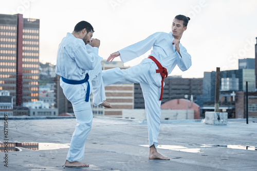 Men, fight and kick in karate class, training and speed with sparring partner, workout and morning on city rooftop. Martial arts team, contest and fitness with block for exercise, coaching or sports photo
