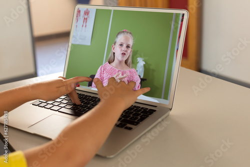 Mid section of a boy using laptop while having a video call with caucasian girl at home photo