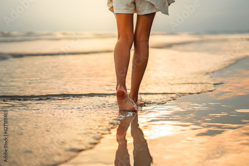 Fototapeta Naklejka Na Ścianę i Meble -  Closeup of woman feet walking on sand beach during a golden hour sunset. Travel and relaxing in summer	