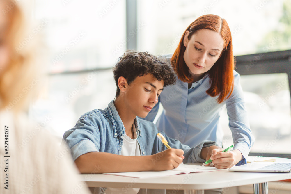 Young pensive school teacher explaining something to smart teenager. Education concept Young pensive school teacher explaining something to smart teenager. Education concept