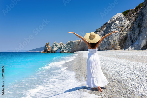 A elegant tourist woman in a white summer dress enjoys the beautiful beach of Lalaria, Skiathos island, Greece photo