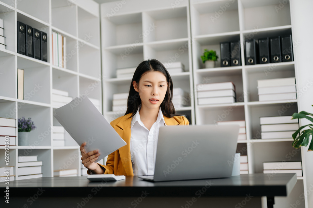 Asian businesswoman working in the modern office with working notepad, tablet and laptop documents Asian businesswoman working in the modern office with working notepad, tablet and laptop documents