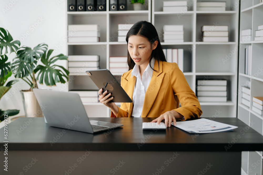 Asian businesswoman working in the modern office with working notepad, tablet and laptop documents Asian businesswoman working in the modern office with working notepad, tablet and laptop documents