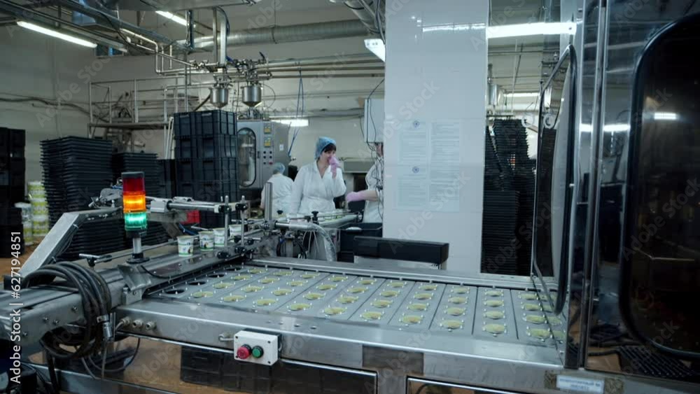 Modern dairy products. A conveyor line in a modern industrial plant. Small containers. Dessert production. Automated line in modern dairy production. Modern equipment. Food industry. Close up Modern dairy products. A conveyor line in a modern industrial plant. Small containers. Dessert production. Automated line in modern dairy production. Modern equipment. Food industry. Close up