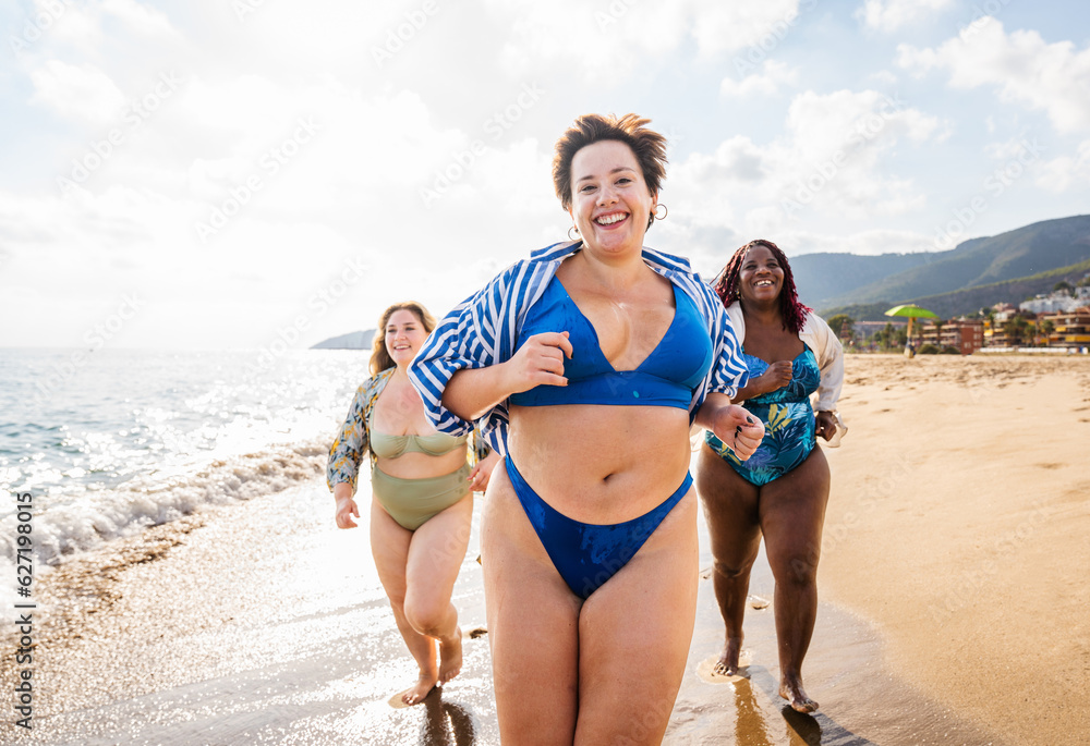 Group of plus size women with swimwear at the beach - Multiethnic curvy adult female having fun and sunbathing on summertime vacation, concepts about beauty, body positivity and self acceptance Group of plus size women with swimwear at the beach - Multiethnic curvy adult female having fun and sunbathing on summertime vacation, concepts about beauty, body positivity and self acceptance