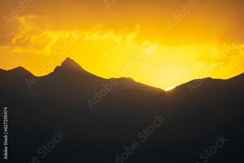 Beautiful fiery sunset. The sun goes down the mountain