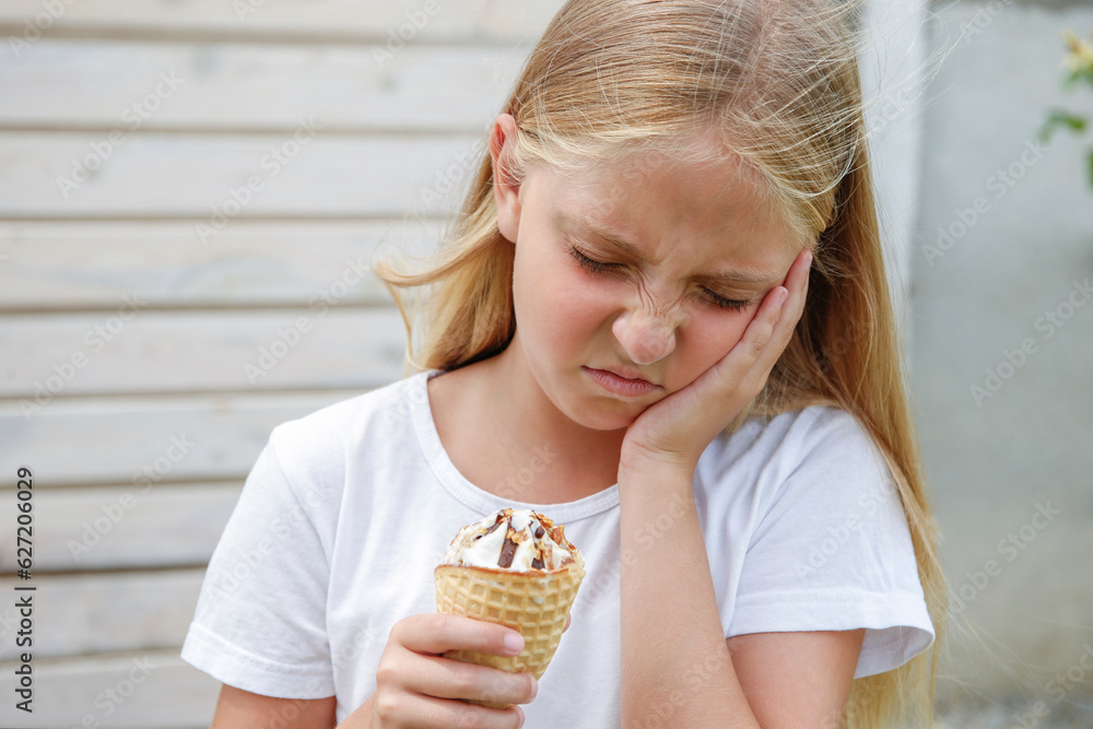 Girl has a toothache from cold ice cream. Stock Photo Adobe Stock