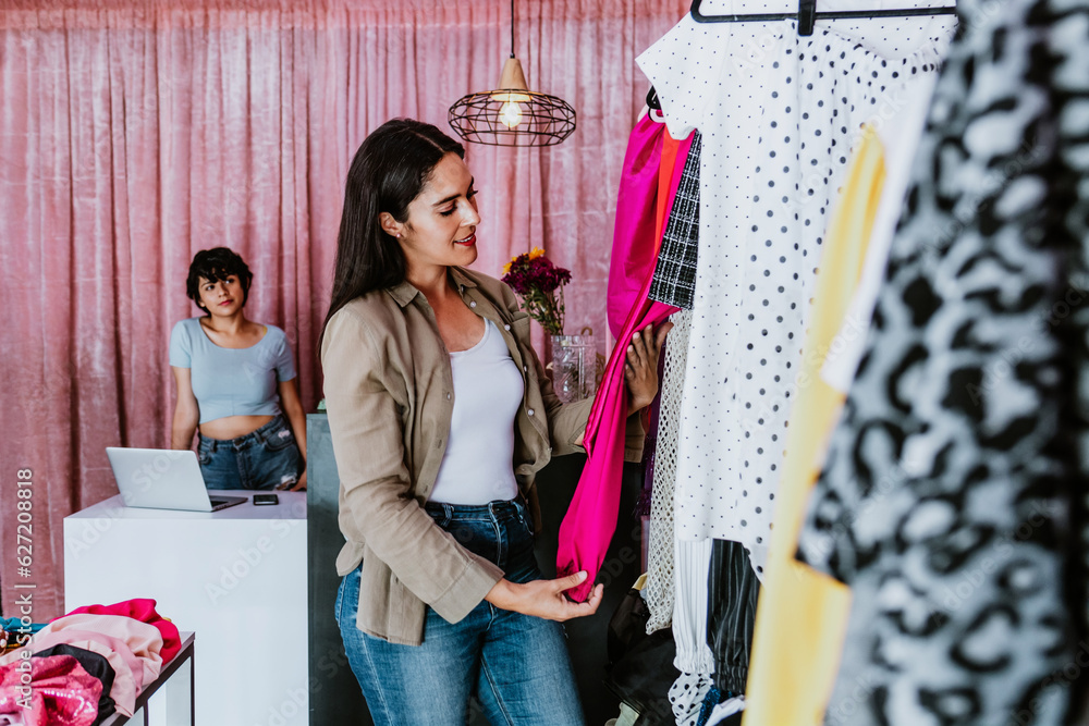 latin woman customer shopping in Clothing Store choosing and trying on